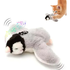 A playful orange kitten interacts with a plush grey bird cat toy that features exaggerated eyes, sound and motion effects, and colorful musical notes to indicate interactive play.