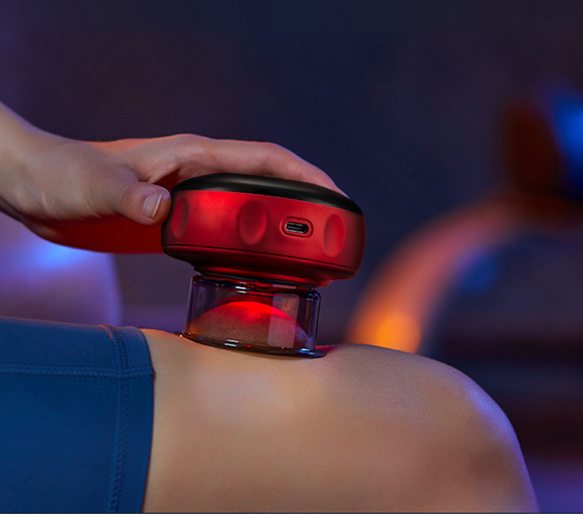 Person using a red light device on their shoulder against a dark background