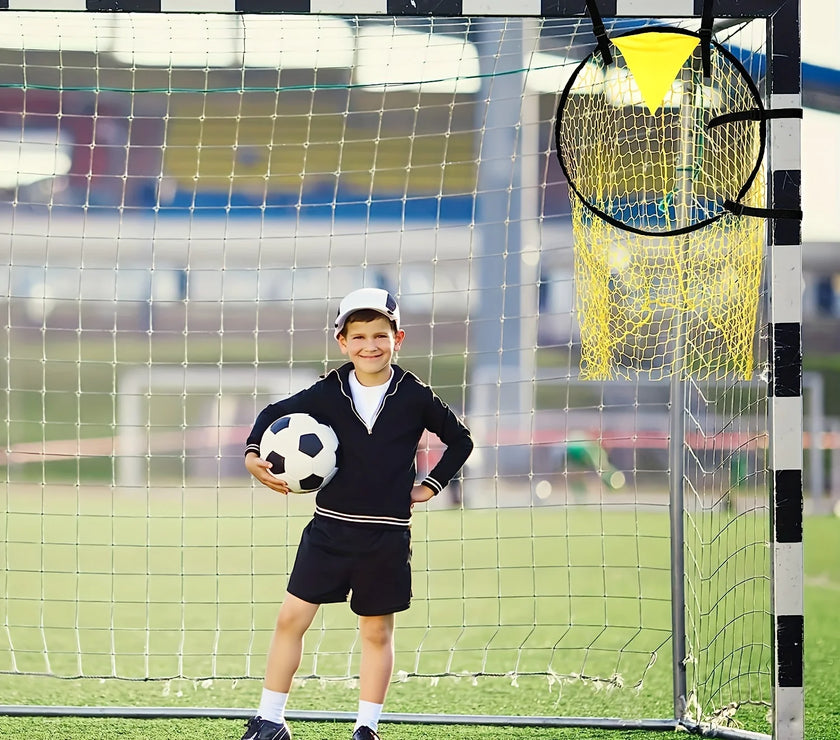 Child holding a soccer ball in front of a goal with a yellow training aid.
