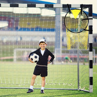 Child holding a soccer ball in front of a goal with a yellow training aid.
