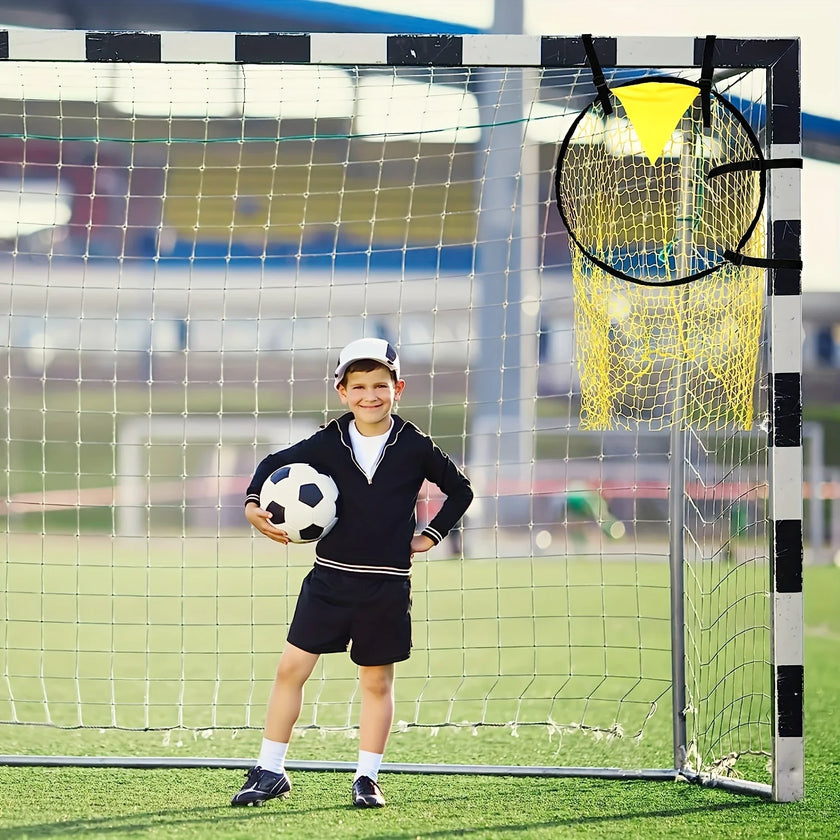 Child holding a soccer ball in front of a goal with a yellow training aid.