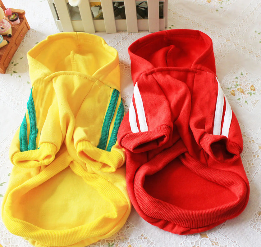 Yellow and red pet hoodies with white stripes on a floral surface