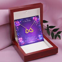 Gold infinity heart necklace displayed in a gift box on a purple Valentine-themed background symbolizing endless love.