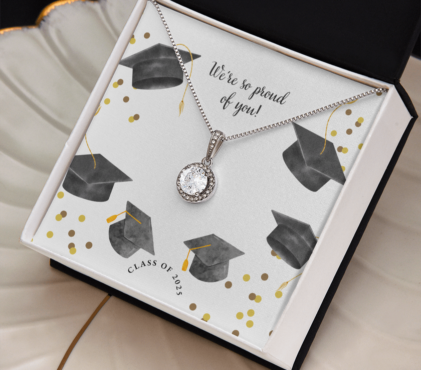 Open gift box displaying a sparkling silver Eternal Hope necklace with a round pendant, set against a graduation-themed message card that reads "We're so proud of you!" with graduation caps, gold confetti, and "Class of 2025" text.
