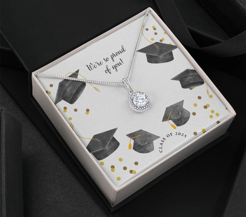 Open gift box displaying a sparkling silver Eternal Hope necklace with a round pendant, set against a graduation-themed message card that reads "We're so proud of you!" with graduation caps, gold confetti, and "Class of 2025" text.