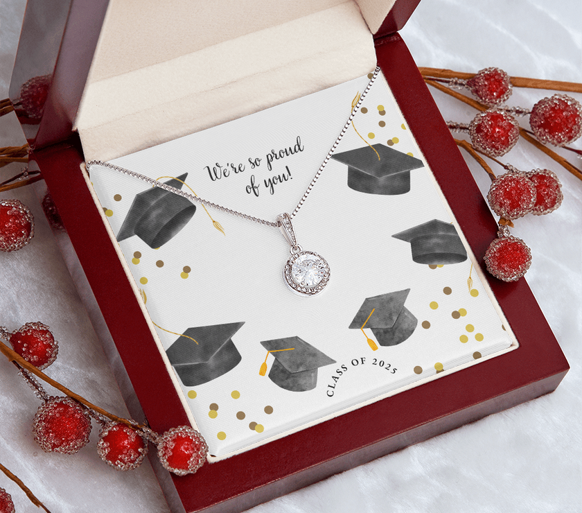 Open gift box displaying a sparkling silver Eternal Hope necklace with a round pendant, set against a graduation-themed message card that reads "We're so proud of you!" with graduation caps, gold confetti, and "Class of 2025" text.