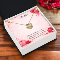 Gold love knot necklace with a sparkling center stone displayed in a  gift box on a soft Valentine-themed background with hearts and romantic message card.