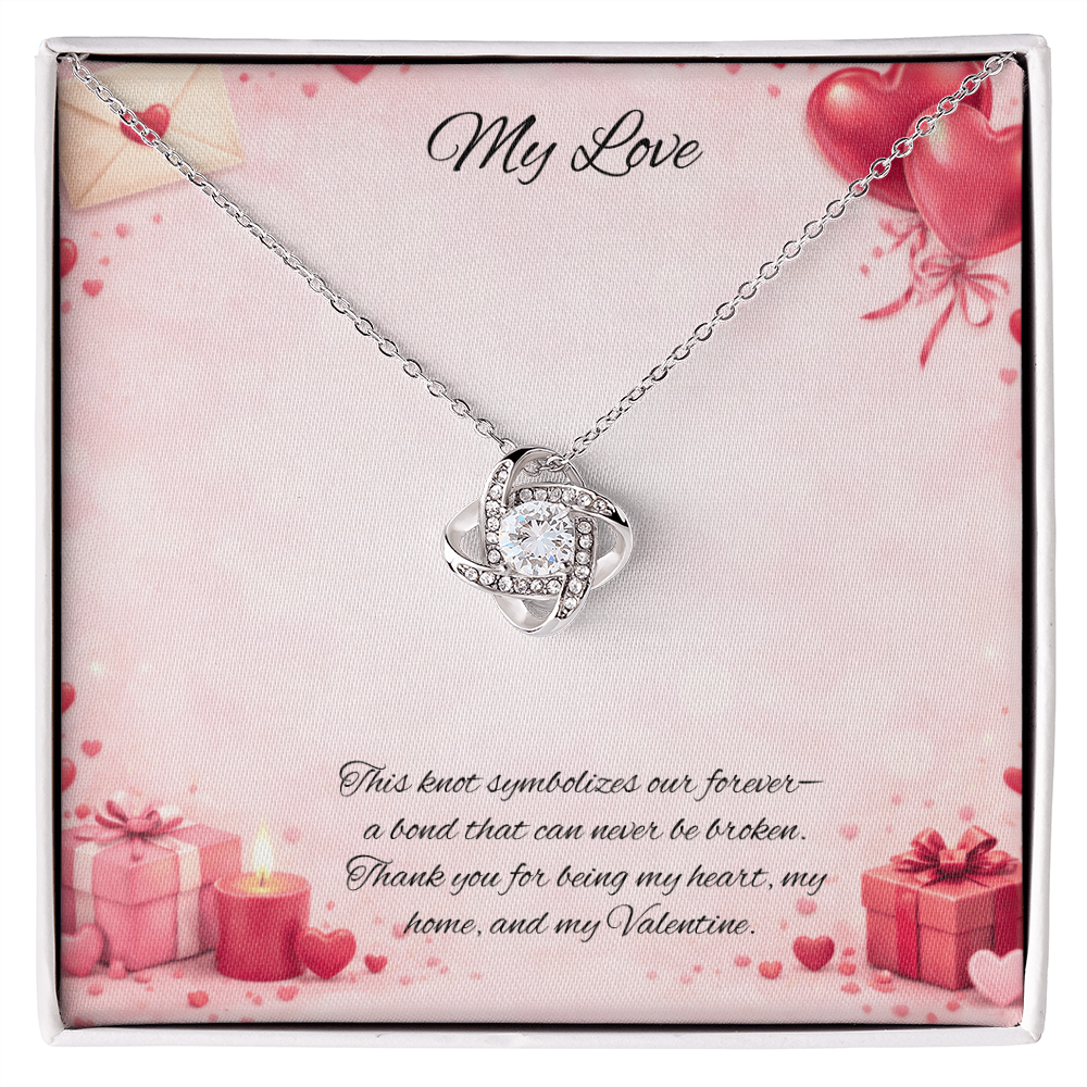 Silver love knot necklace with a sparkling center stone  on a soft Valentine-themed background with hearts and romantic message card.
