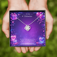 Silver love knot necklace with a sparkling center stone displayed on a purple Valentine’s Day background with glowing hearts, symbolizing eternal love and romantic connection.