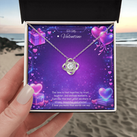 Silver love knot necklace with a sparkling center stone displayed on a purple Valentine’s Day background with glowing hearts, symbolizing eternal love and romantic connection.