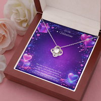Silver love knot necklace with a sparkling center stone displayed on a purple Valentine’s Day background with glowing hearts, symbolizing eternal love and romantic connection.