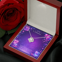Silver love knot necklace with a sparkling center stone displayed on a purple Valentine’s Day background with glowing hearts, symbolizing eternal love and romantic connection.