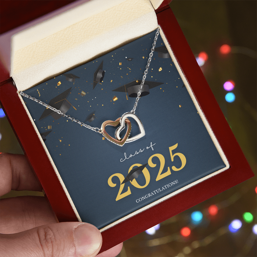 A gold interlocking hearts necklace displayed in a cherry wood box with a message card that reads "Class of 2025 – Congratulations" featuring graduation caps and celebratory confetti.