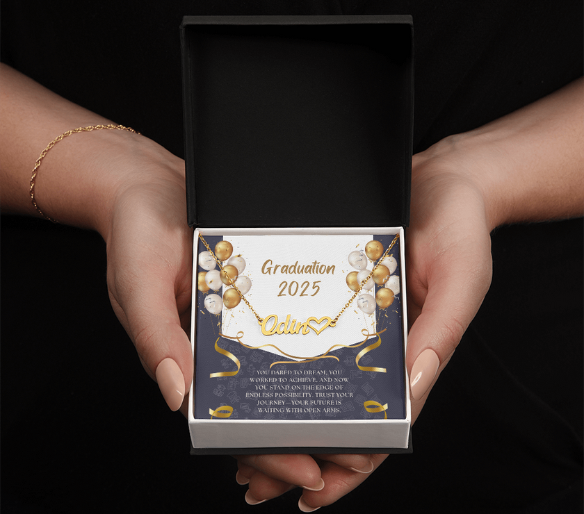 Close-up of hands holding a 
personalized gold name necklace with heart, set against a message card that reads "Graduation 2025" and includes an inspiring graduation quote, with gold and white balloons in the background.