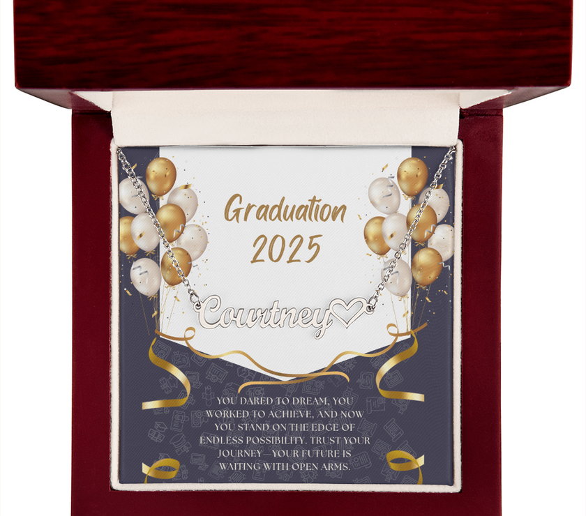 Close-up of hands holding an open red gift box featuring a personalized silver name necklace with heart, set against a message card that reads "Graduation 2025" and includes an inspiring graduation quote, with gold and white balloons in the background.