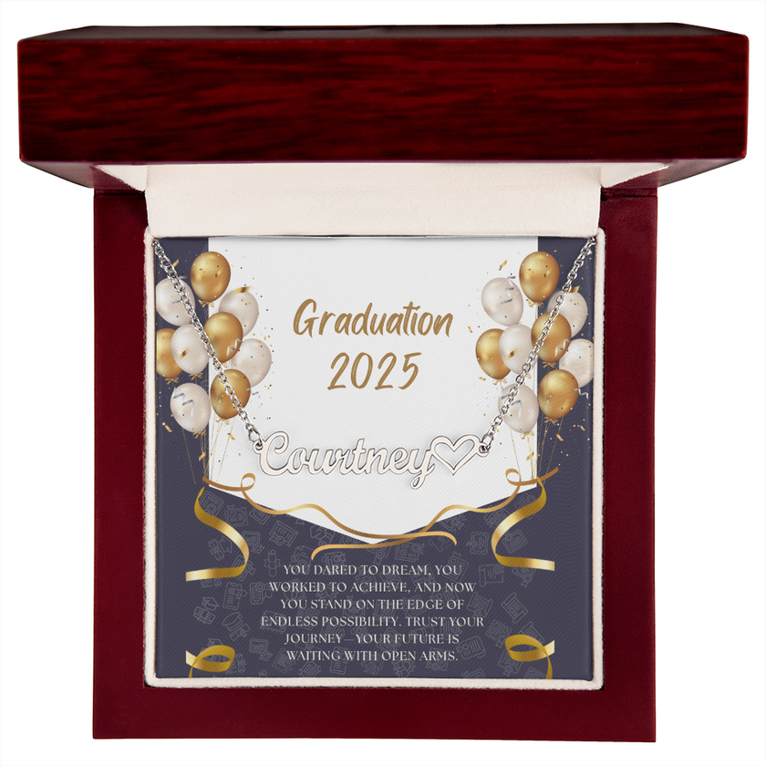 Close-up of hands holding an open red gift box featuring a personalized silver name necklace with heart, set against a message card that reads "Graduation 2025" and includes an inspiring graduation quote, with gold and white balloons in the background.