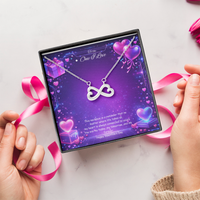 Silver infinity heart necklace displayed in a gift box on a purple Valentine-themed background symbolizing endless love.