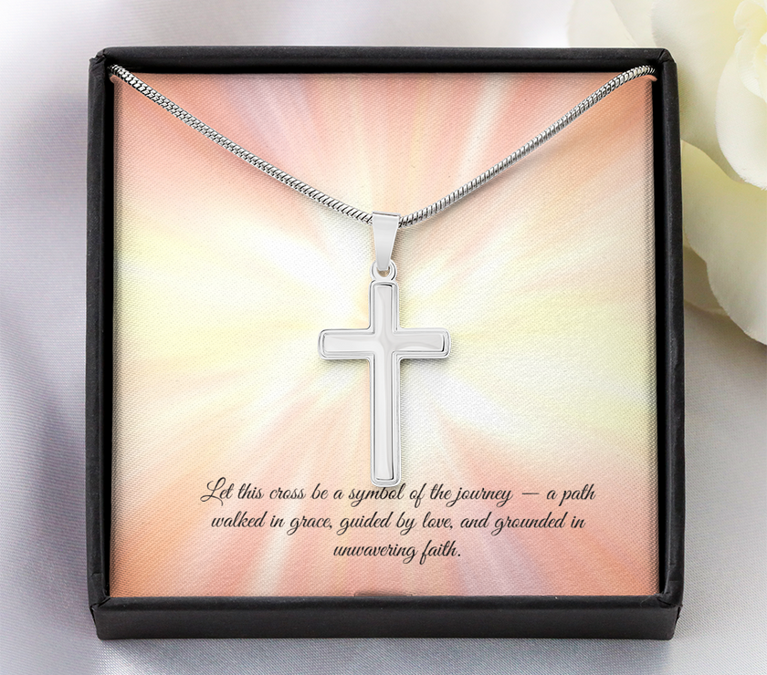 Silver cross necklace displayed in a red gift box with a radiant background and an inspirational message that reads: 'Let this cross be a symbol of the journey — a path walked in grace, guided by love, and grounded in unwavering faith