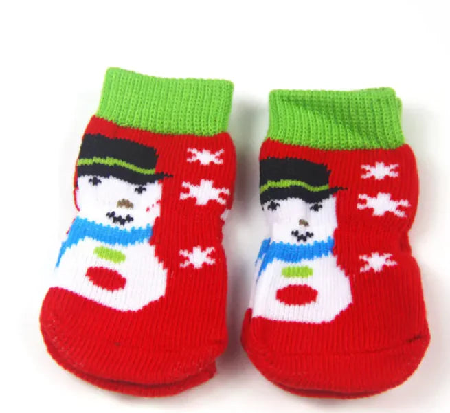 Red pet socks with snowman design and green cuffs on a white background