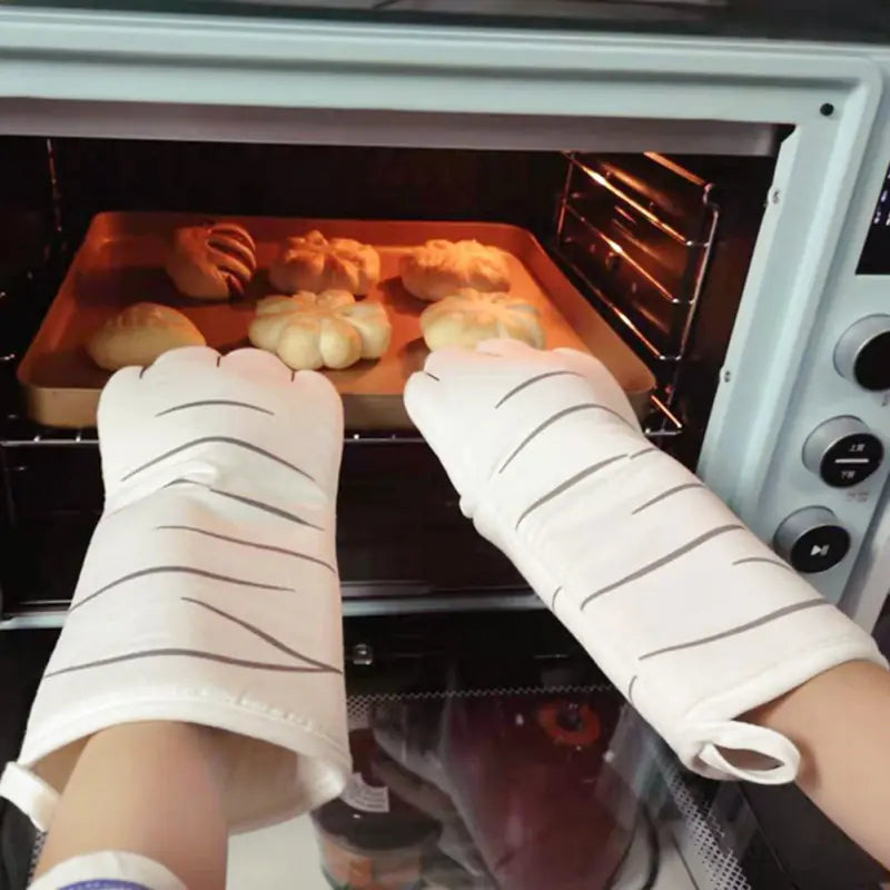 Person wearing oven mitts opening an oven with a tray of bread inside.