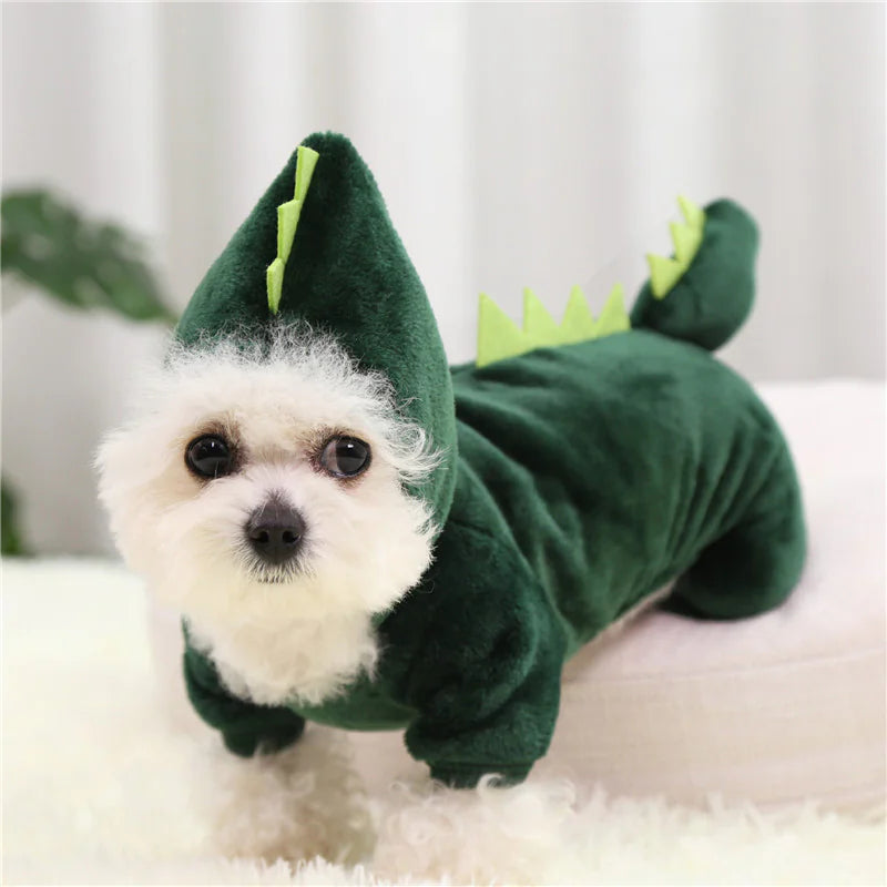 Dog wearing a green dinosaur costume on a white surface