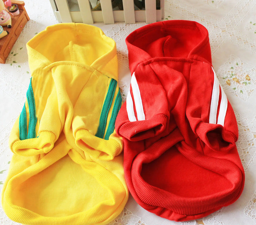 Yellow and red pet hoodies with white stripes on a floral surface